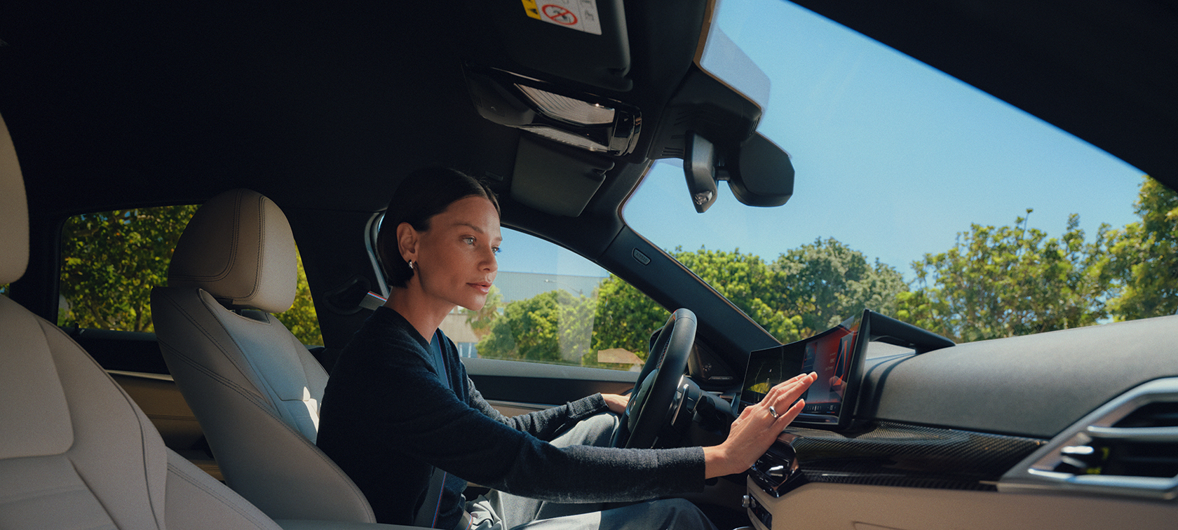 Eine Frau sitzt in einem BMW und bedient das Display.