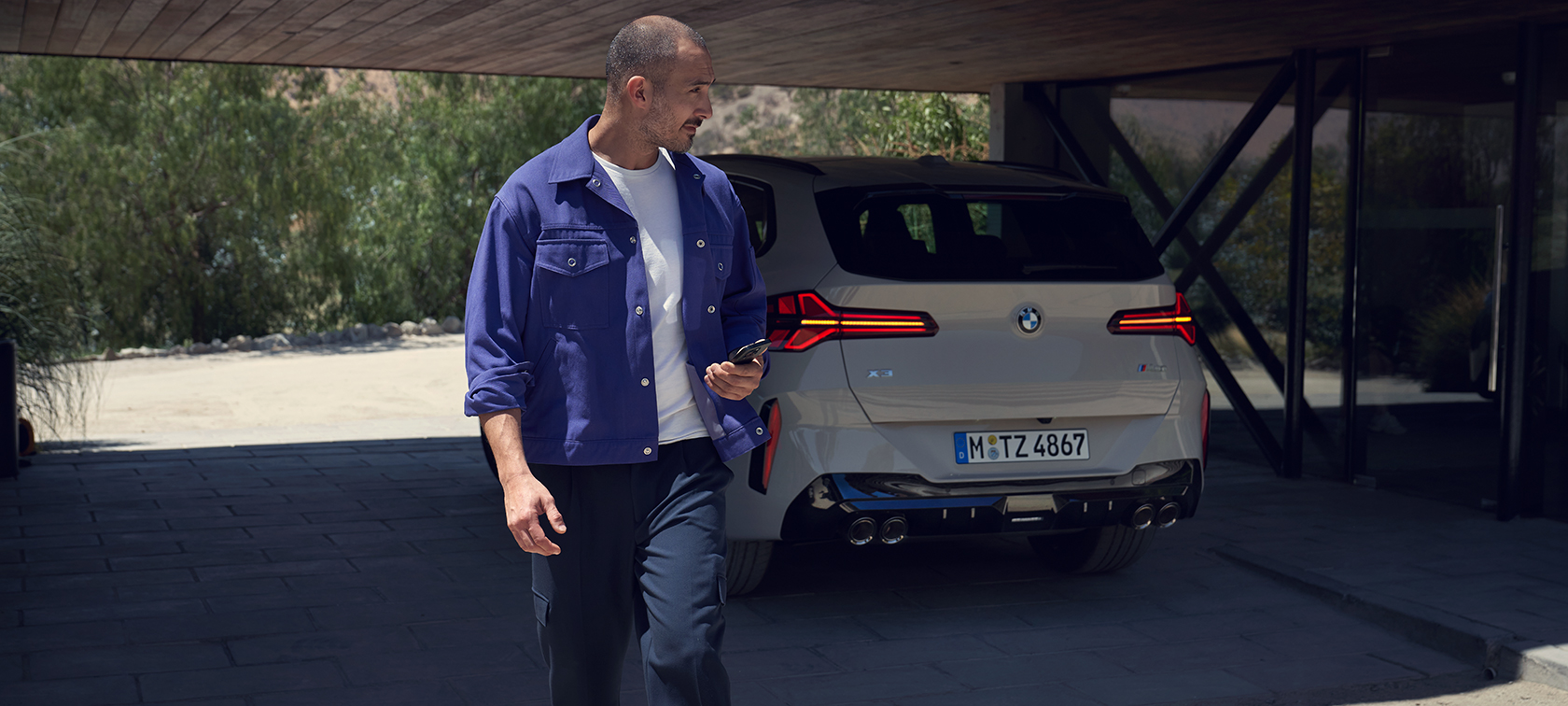 Ein Mann geht entspannt von einem BMW weg.